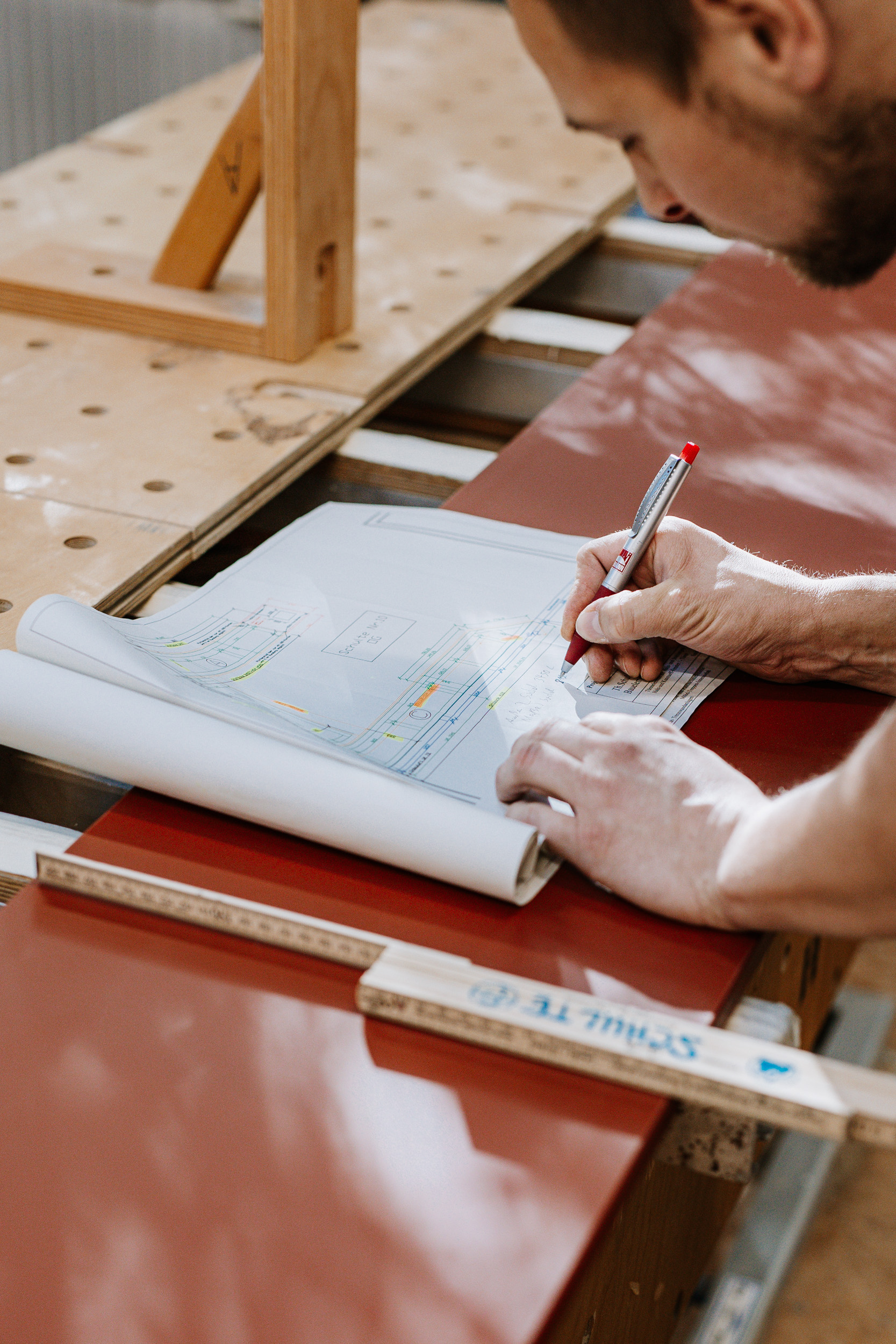 Ein Mitarbeiter macht sich Notizen in Plänen.