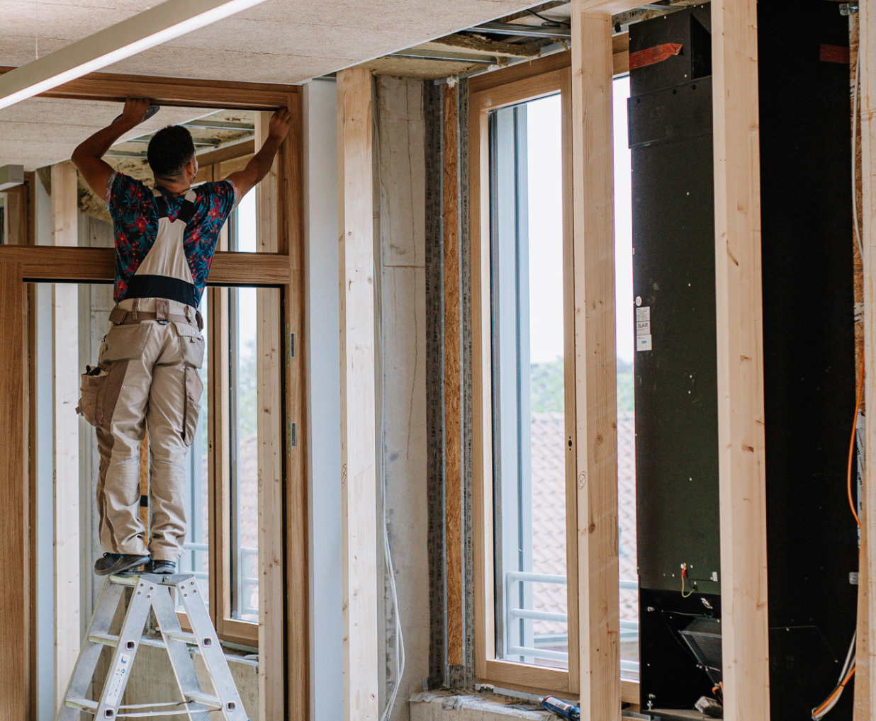 Ein Mitarbeiter baut einen Holzfensterrahmen ein.