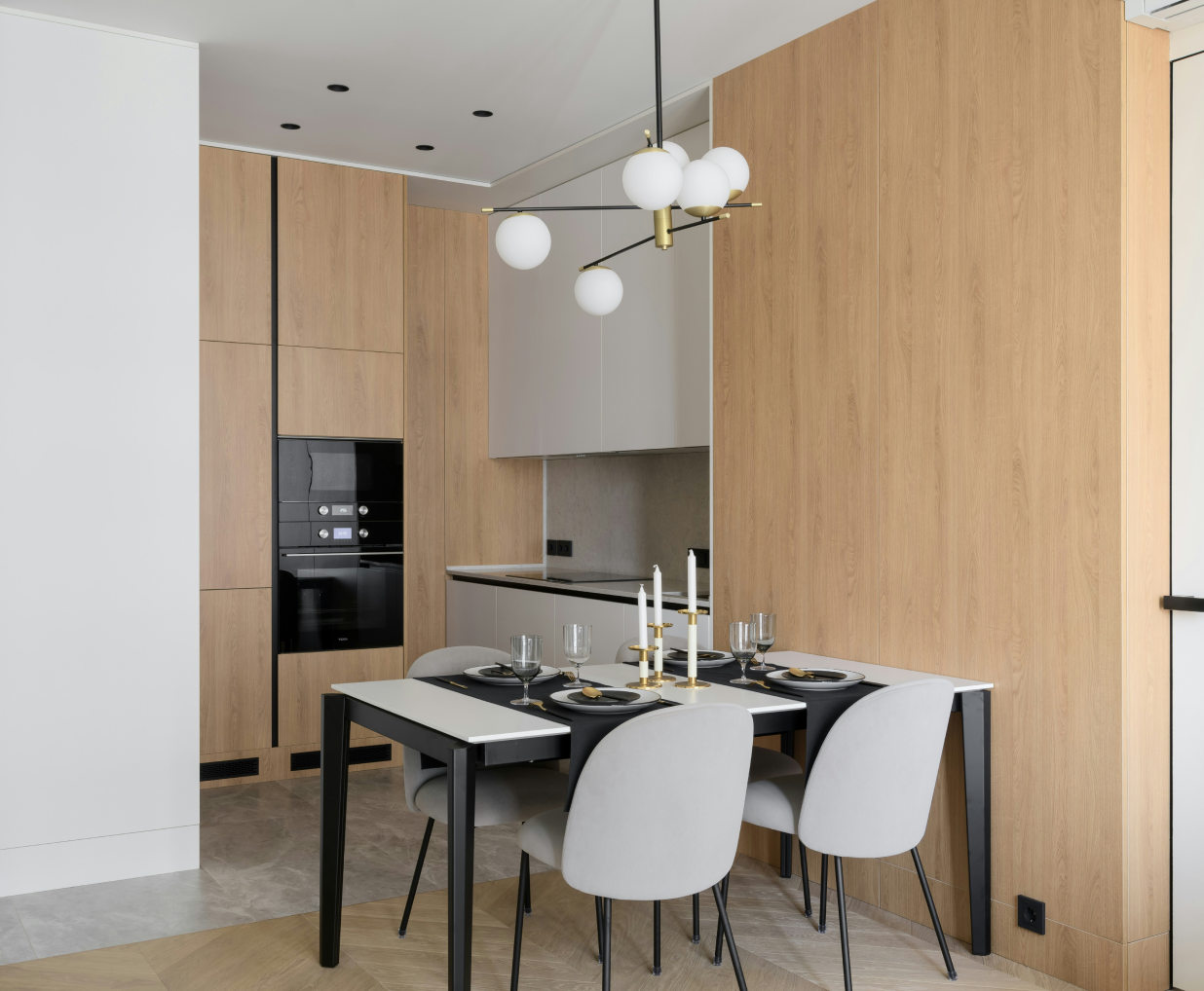 Eine Holzküche mit grauen Akzenten und einem Esszimmertisch mit grauen Stühlen.