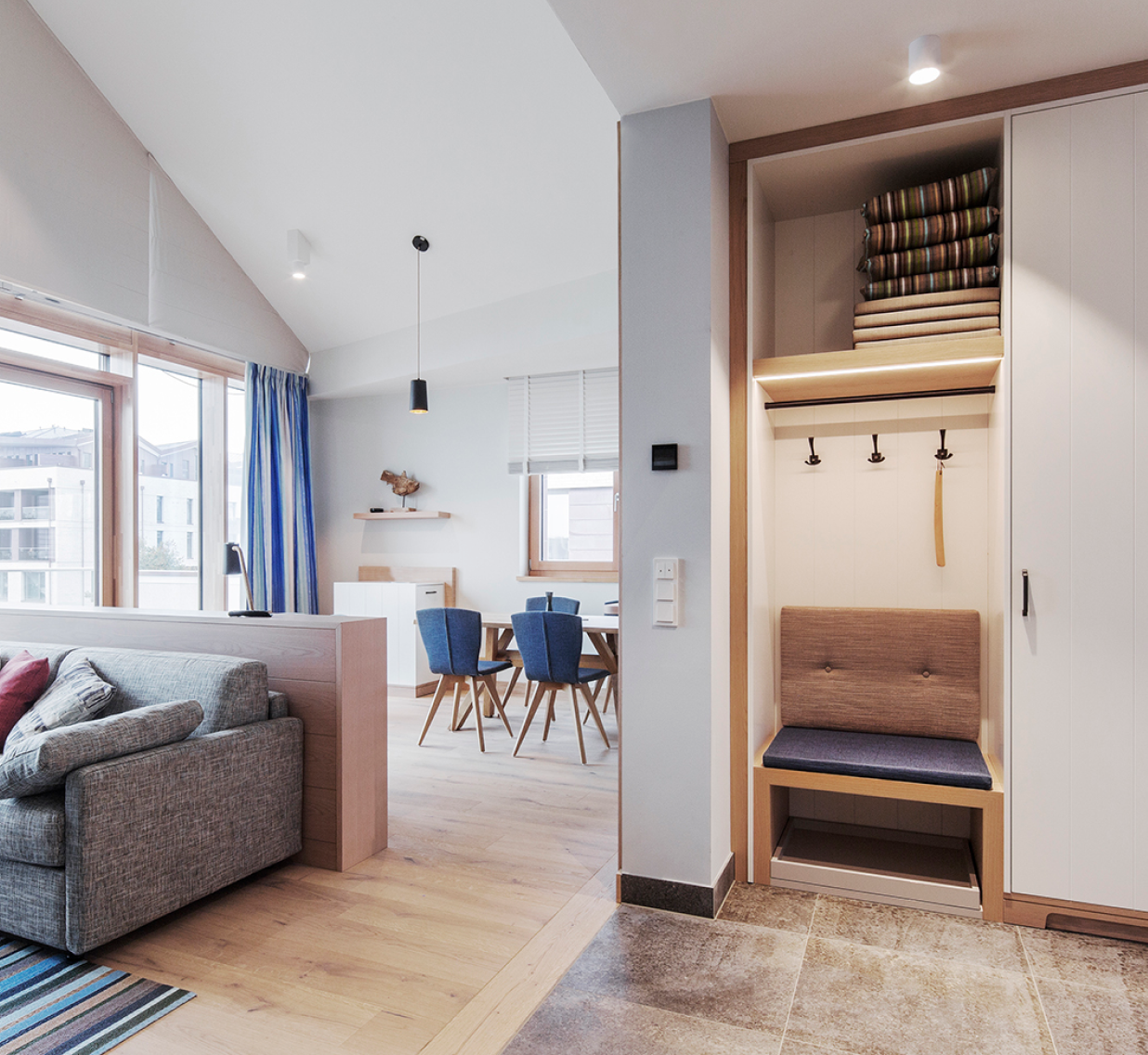 Eingangsbereich eines Hotelzimmers mit Holzsitzecke und Holzraumtrenner.