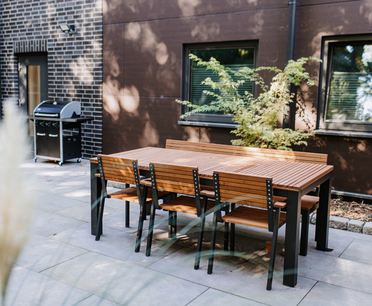 Outdoor Sitzarea mit Holztisch, Holzstühlen und einer Holzbank.