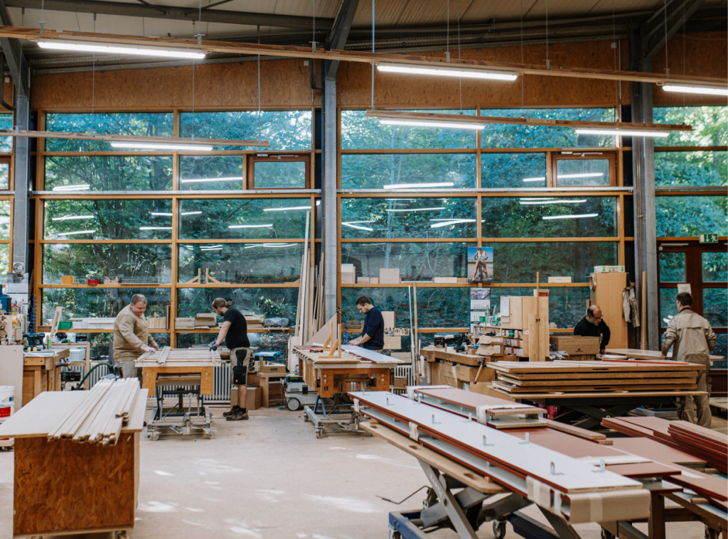 Raumaufnahme der Tischlerei, Mitarbeiter arbeiten an verschiedenen Projekten.